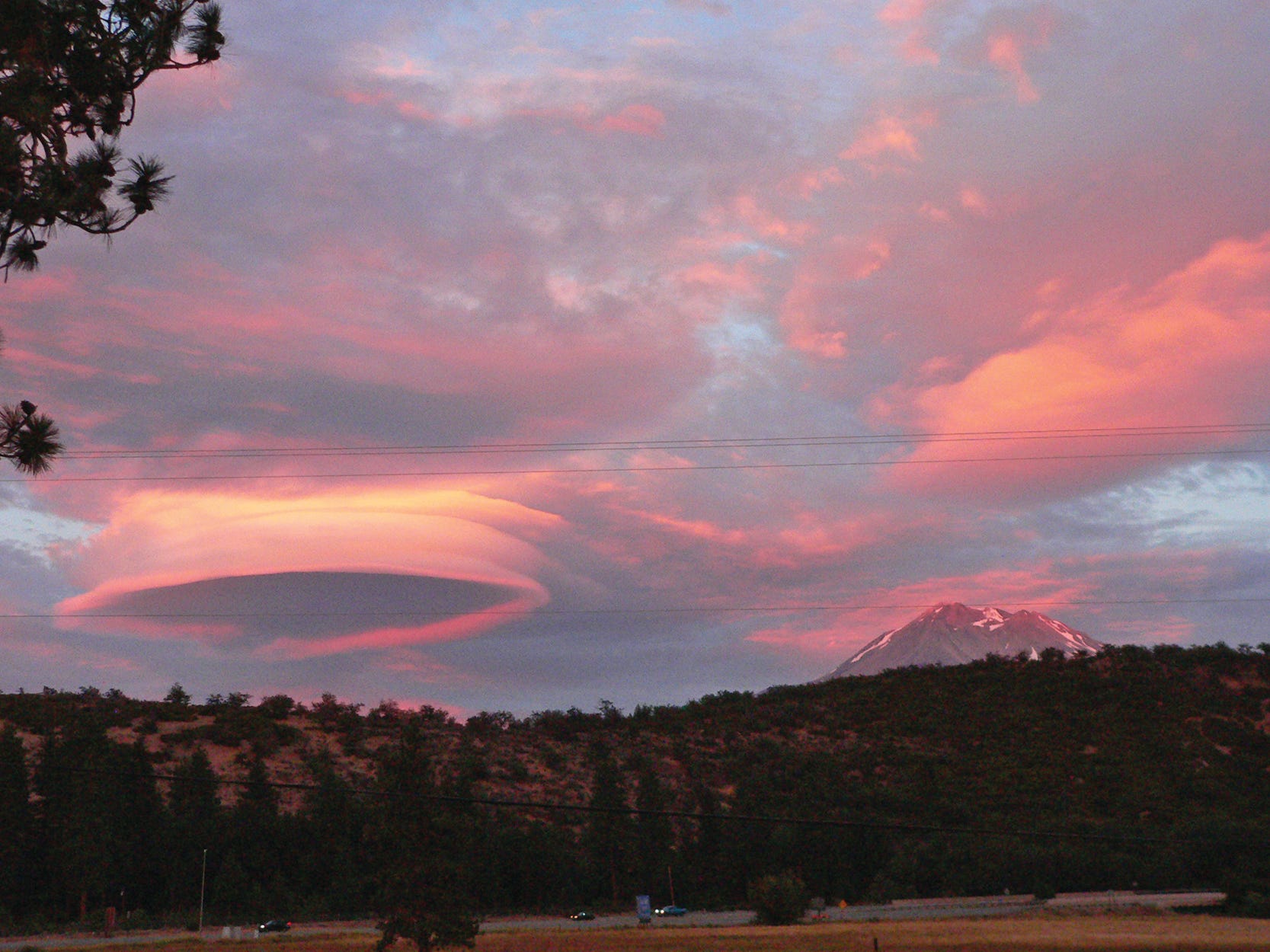 The last rays of the day's sun make Mt. Shasta and a disc-shaped lenticular glow pink.